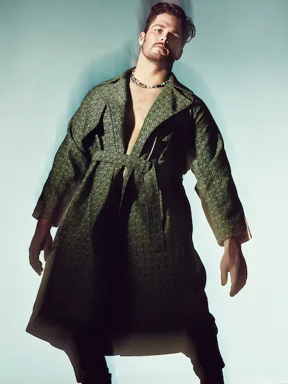 El modelo y jugador de fútbol americano Jon Toth viste abrigo de algodón negro y verde con anagrama All Over de Loewe. Collares de Bershka.