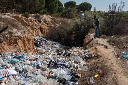 Un joven subsahariano lanza una bolsa de basura al vertedero del asentamiento El Bosque, en Lucena del Puerto.