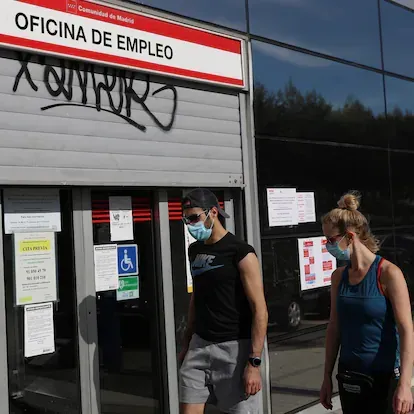 MADRID, 05/05/2020.- Dos jóvenes pasan ante una ofician de empleo este martes en Madrid. La Seguridad Social perdió 947.896 afiliados desde que comenzó la crisis del COVID-19 y hasta el cierre de abri