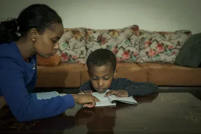Rahim Teshome ayuda a su hijo, de seis años, a realizar las actividades escolares en el interior de su casa. “Tengo mucho miedo por él, pero debo garantizarle un lugar seguro. Si aquí el Estado no se 