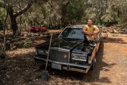 Liam Aldous, director creativo de ColourFeel, en la casa que está restaurando con otras personas en el interior de la isla de Ibiza. En la foto posa con uno de los coches antiguos que tienen en el ter