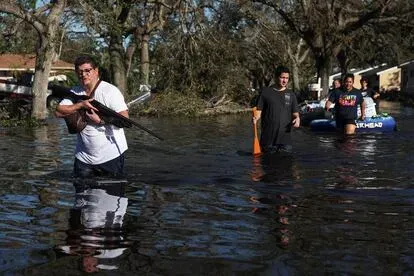 Un hombre caminaba con una escopeta por una calle inundada de North Port (Florida), el viernes.