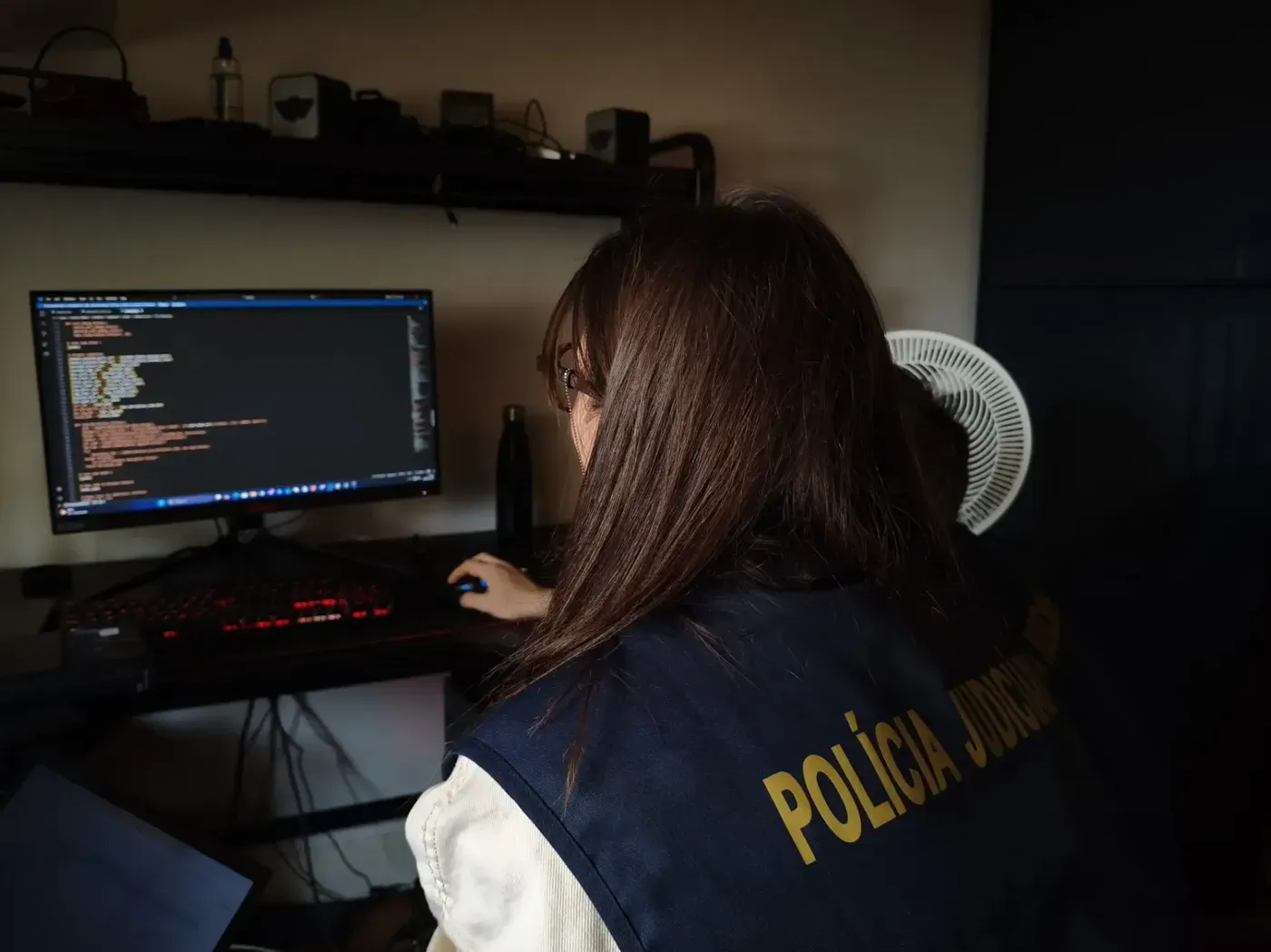 A European police officer examining a computer at the home of a forum member.