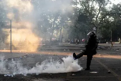 Un carabinero patea una granada lacrimógena.