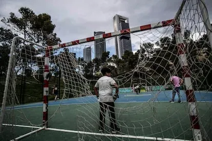 Unos chicos juegan al fútbol en un parque del barrio de La Ventilla, con las torres de plaza de Castilla al fondo.