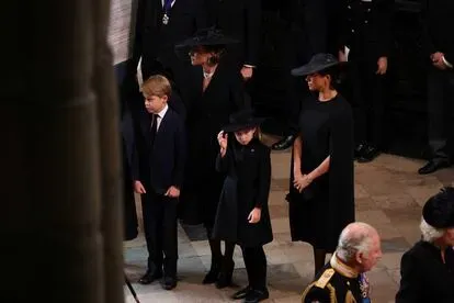 Los príncipes Jorge y Carlota, delante de su madre Kate Middleton y su tía, Meghan Markle, esperan la entrada del féretro de la reina Isabel en la abadía de Westminster .