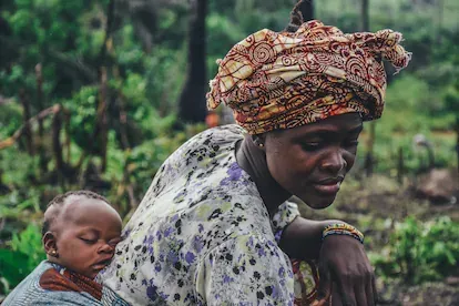 Una mujer con su bebé a cuestas en una plantación de yuca en Sierra Leona.