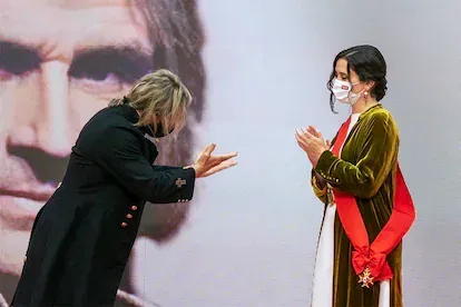 Isabel Díaz Ayuso recibe una medalla del músico Nacho Cano durante los eventos del Dos de Mayo en la sede de la Comunidad de Madrid.