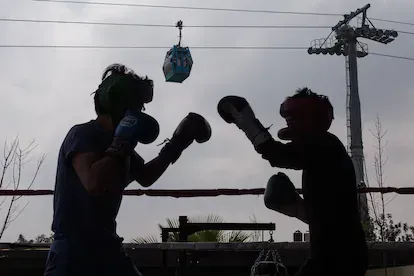 Dos vecinos practican boxeo, en un parque cercano a una de las estaciones del cablebús.