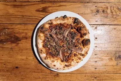 Pizza 'Futuro di marinara', con crema de tomate asado, aceitunas de Caiazzo, anchoas de Trapani, pesto de ajos silvestres, alcaparras de Salina y orégano de los montes Lattari.