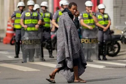 Un hombre que vivía en el mercado de drogas en la plaza Princesa Isabel cruza una calle con una manta después de que la policía allanó el mercado en el centro de Sao Paulo, el 11 de mayo de 2022.