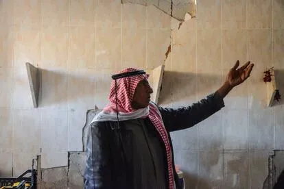 Husain Madat, de 72 años, señala una pared de su casa, muy dañada por los enfrentamientos de enero de 2022 entre fuerzas kurdas y combatientes del ISIS. Este hombre de 72 años vive con su esposa y tre