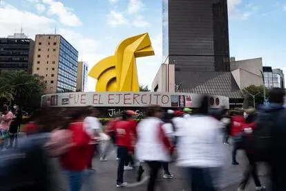 Manifestantes caminan frente a la escultura del "Caballito", que fue pintada durante la marcha con la frase "Fue el ejército".