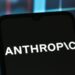 Anthropic logo on a black phone in front of a rainbow background