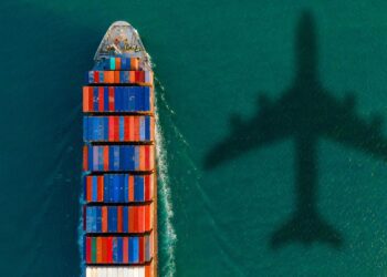A shipping boat and shadow of a shipping plan in green water.