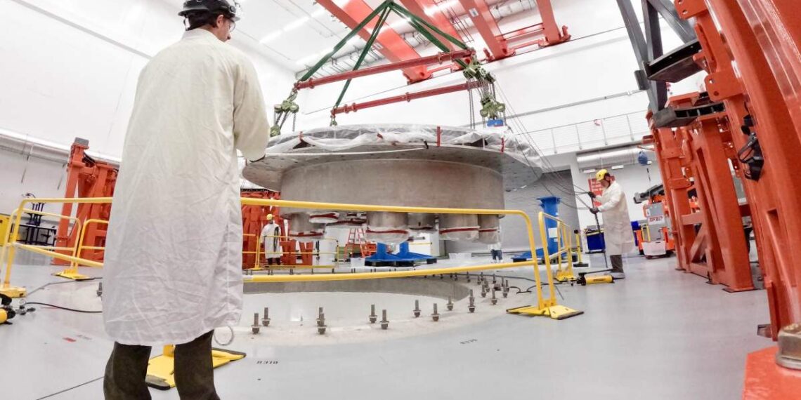 Commonwealth Fusion Systems employees supervise the installation of the tokamak's cryostat base.