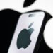 In this photo illustration, the logo of Apple Inc. is displayed on a smartphone screen, with the company's iconic black apple symbol visible in the background.