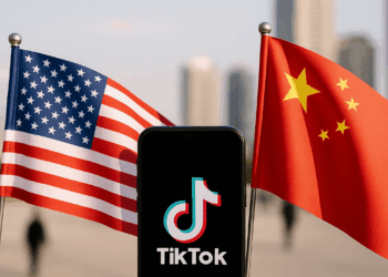 The TikTok app and logo are seen on a mobile device in front of a US flag