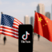 The TikTok app and logo are seen on a mobile device in front of a US flag