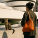 Two set of hands hold an orange handbag.