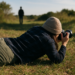 A woman is buried in sand; you see only her arms, hair, and a wire to push the camera button.